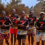 5 Ugandan boys running on a sand road